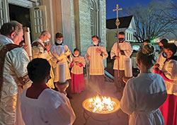 Altar servers and Deacon Thomas Hill, left, surround a fire outside of St. Joseph Church in Shelbyville on April 3 while Father Michael Keucher, St. Joseph Parish&rsquo;s pastor, prays at the start of the faith community&rsquo;s Easter Vigil. (Submitted photo)