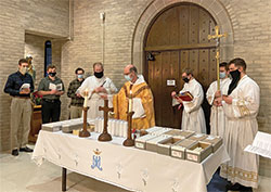With seminarians gathered around him, Benedictine Father Justin DuVall, center, blesses candles on Feb. 2 at Bishop Simon Brut&eacute; College Seminary in Indianapolis. The archdiocesan-operated college seminary experienced challenges during the past year as it sought to form men for the priesthood during the coronavirus pandemic. (Submitted photo)