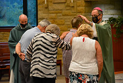 Archbishop Charles C. Thompson ritually lays his hands upon Mark John during the archdiocese&rsquo;s annual Substance Addiction Ministry (SAM) Mass, held this year at St. Bartholomew Church in Columbus on Aug. 12. Father Christopher Wadelton, pastor of St. Bartholomew, looks on as Denny, left, and Debbie Frey and Mark&rsquo;s wife Sue join in the blessing. The Johns are members of St. Ambrose Parish in Seymour. Their friends, the Freys, are members of St. Joseph Parish in Shelbyville. (Photo by Natalie Hoefer)