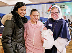 Sister of Life Lucia Christi smiles while holding a newborn during a Christmas party while serving a two-year mission at the Sisters of Life&rsquo;s crisis pregnancy center in New York City, where they provide support to pregnant women in crisis and offer continuing support to them following the birth of their children. (Submitted photo courtesy of the Sisters of Life)
