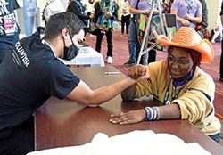 Seminarian Alex Lindbergh, a freshman at Bishop Brut&eacute; College Seminary in Indianapolis, arm wrestles Asia Carmon of the Diocese of Raleigh, N.C., during the National Catholic Youth Conference on Nov. 20 at the Indiana Convention Center in Indianapolis. (Photo by Sean Gallagher)