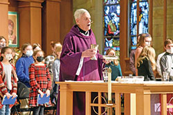 Father Robert Sims, pastor of Immaculate Heart of Mary Parish in Indianapolis, prays the eucharistic prayer during a school Mass on Dec. 17, 2021, in his parish&rsquo;s church. The day was the 50th anniversary of his ordination as a priest. (Photo by Sean Gallagher)