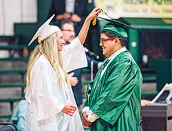 During the graduation ceremony of Father Michael Shawe Memorial High School in Madison in 2021, Lillian Heath turns the tassels from one side to the other on the graduation cap of fellow senior Leonel&nbsp;Rios-Amaro&mdash;displaying a longstanding tradition among seniors at Shawe to show that they have now graduated. (Photo courtesy of Laura Jayne Gardner Photography)