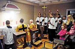 Father Jonathan Meyer, co-pastor of All Saints Parish in Dearborn County, second from left, and Deacon Robert Decker join several altar servers and other parishioners in praying before the Blessed Sacrament on March 1, 2017, the day on which the Batesville Deanery faith community&rsquo;s perpetual adoration chapel on its St. John the Baptist campus in Dover was inaugurated. (File photo by Sean Gallagher)