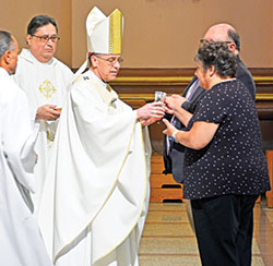Archbishop Charles C. Thompson receives the gifts from Joy and Steve Day, members of Holy Spirit Parish in Indianapolis, during a Mass for members of the United Catholic Appeal&rsquo;s Miter Society and the archdiocesan Catholic Community Foundation&rsquo;s Legacy Society at SS. Peter and Paul Cathedral in Indianapolis on May 12. (Photo by Natalie Hoefer)