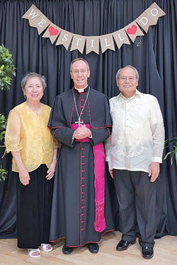Celia and Domingo Conlu, members of St. Simon the Apostle Parish in Indianapolis, pose for a photograph with Archbishop Charles C. Thompson during a reception in the Archbishop Edward T. O&rsquo;Meara Catholic Center in Indianapolis after the archdiocese&rsquo;s 38th annual Wedding Anniversary Mass on Aug. 14 across the street at SS. Peter and Paul Cathedral. The couple has been married for 50 years. (Submitted photo by Richard Corona)