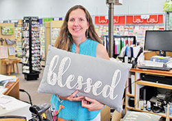 Store owner Tina Sherman holds a pillow  with the word &ldquo;Blessed&rdquo; in The Ark Book and Gift Store in Columbus. (Photo by Jennifer Lindberg)