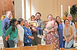 Dr. Michael Padilla, center, smiles with his family in SS. Peter and Paul Cathedral in Indianapolis after receiving the archdiocese&rsquo;s Archbishop O&rsquo;Meara Respect Life Award during the Respect Life Mass on Oct. 2. Among those posing with him are his wife Dana (holding their son Gabe) their daughter Mary Elise (holding the award) and his parents Lourdes and Mike Padilla, third from right and far right, respectively. (Photo by Natalie Hoefer)