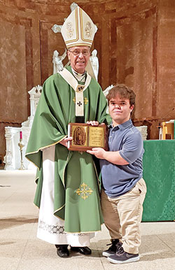 Eric Dessauer smiles as he receives the archdiocese&rsquo;s Our Lady of Guadalupe Pro-Life Youth Award presented to him by Archbishop Charles C. Thompson during the Respect Life Sunday Mass in SS. Peter and Paul Cathedral in Indianapolis on Oct. 2. (Photo by Natalie Hoefer)