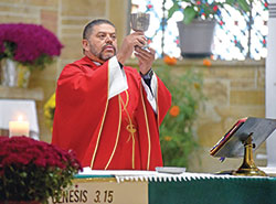 Father Juan Valdes, pastor of St. Anthony Parish in Indianapolis, elevates a chalice on Oct. 19 during a Mass in his parish&rsquo;s church. (Photo by Sean Gallagher)