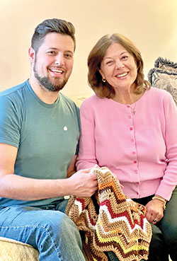 Tony Burkhart and his mother Janine Schorsch hold a prayer blanket that was made by the Ladies Sodality Prayer Shawl Ministry of All Saints Parish in Dearborn County. When Burkhart was at the edge of death in a hospital, Schorsch rushed to bring the blanket to him, wanting her son to be wrapped in prayers and God&rsquo;s grace. (Submitted photo)