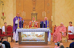 Father Douglas Hunter, left, Archbishop Charles C. Thompson, Father Nicholas Dant and Father James Wilmoth extend their hands during the eucharistic prayer of a special Mass on Dec. 11 at St. Roch Church in Indianapolis marking the parish&rsquo;s 100th anniversary of its founding. Kneeling in back are altar servers Ezekiel Littell, left, and Isaiah Littell, far right. (Photo by Natalie Hoefer)