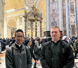 Archdiocesan seminarians Khaing Thu, left, and Samuel Hansen stand on Jan. 3 in St. Peter&rsquo;s Basilica at the Vatican after praying before the mortal remains of Pope Benedict XVI. (Submitted photo)