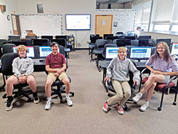 Eli Pac, left, Thomas Nguyen, Tessa Mize and Lauren Koleszar, all eighth-graders at St. Barnabas School in Indianapolis, sit in their school&rsquo;s computer classroom. They worked to develop a website and app that will help Hakha Chin Catholics in Indianapolis, Myanmar and around the world to pray and grow in their faith. (Submitted photo)