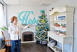 April Haskett, executive director of Hope Resource Center in Bedford, points out the cabinet of free items in the pregnancy care center&rsquo;s welcoming lobby on a day when those served by the organization were invited to come to the facility for free family Christmas photo shoots on Nov. 23, 2022. (Photo by Natalie Hoefer)