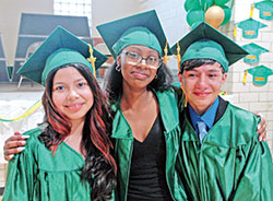 After their graduation ceremony at Holy Cross Central School in Indianapolis on May 24, Ashley Aguilar Perez, left, Ashaundi Copeland and Elkin &ldquo;Santiago&rdquo; Vera Lamprea share a moment of togetherness. (Photo by John Shaughnessy)
