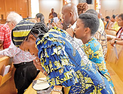 Aurore&nbsp;Gbetie, a member of St. Christopher Parish in Indianapolis and a native of the African country of Benin, bows in prayer after receiving the Eucharist during a Mass celebrating Africa Day (or Africa Freedom Day) at St. Rita Church in Indianapolis on June 4. (Photo by Natalie Hoefer)