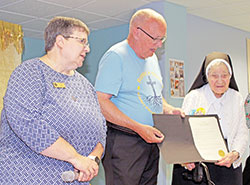 Benedictine Sister Mary Carol Messmer, right, receives a certificate on June 4 from Dennis Buckley, mayor of Beech Grove, declaring June 12 as &ldquo;Sister Mary Carol Day&rdquo; in the city. Benedictine Sister Julie Sewell, prioress of the monastery, looks on&nbsp;at left. (Submitted photos by Jennifer Lindberg)