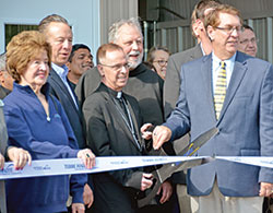 Patricia Etling, left, Terre Haute mayor Duke Bennett (behind Patricia), Archbishop Charles C. Thompson and Catholic Charities Terre Haute agency director John C. Etling cut a ribbon for the opening of Catholic Charities Terre Haute&rsquo;s newly constructed foodbank during a ceremony on April 29, 2019, in Terre Haute. (File photo by Natalie Hoefer)