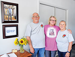Tony Talbert, left, and his wife Donna Talbert, right, pose with Vicky Greer, the mother of David Marshal for whom the new David&rsquo;s House St. Vincent de Paul ministry in Richmond was named. Marshall&rsquo;s photo is seen hanging on the wall. (Photo by Natalie Hoefer)