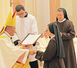 Franciscan Sister M. Evangeline Rutherford ritually receives a ring from Bishop Joseph N. Perry, at the time an auxiliary bishop of the Archdiocese of Chicago, during an Aug. 3 Mass at the chapel of St. Francis Convent in Mishawaka, Ind., during which she professed perpetual vows as a member of the Sisters of St. Francis of Perpetual Adoration. Assisting Bishop Perry is Nick Monin, a seminarian of the Diocese of Fort Wayne-South Bend. Looking on is Franciscan Sister Margaret Mary Mitchel, right, provincial superior of the Perpetual Adoration Franciscans based in Mishawaka. (Submitted photo)