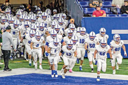 The football team of Bishop Chatard High School in Indianapolis runs onto the field of Lucas Oil Stadium in Indianapolis on Nov. 24, the day when the Trojans defeated the team from Heritage Hills High School to win Indiana&rsquo;s Class 3A championship. (Submitted photo)