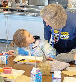 Mila Baker, left, a pre-kindergarten student at St. Roch School in Indianapolis, smiles during a lunch period at Lori Tobin, a member of St. Roch Parish who volunteers in the school&rsquo;s cafeteria. (Submitted photo)
