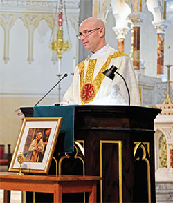 Father Michael Keucher, archdiocesan vocations director, preaches a homily at St. John the Evangelist Church in Indianapolis during a Feb. 9 Mass that was part of the archdiocesan vocations office&rsquo;s third annual Day of Prayer with St. John Vianney for Priestly Vocations. A relic of the patron saint of priests is displayed in front of the ambo. (Photo by Sean Gallagher)