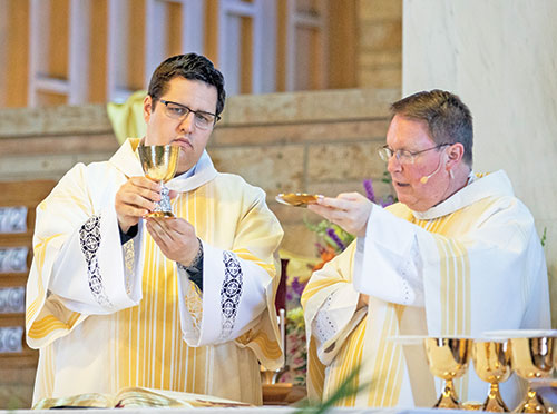 Deacon Anthony Armbruster, left, elevates a chalice at a Mass on April 30, 2023, at Our Lady of Perpetual Help Church in New Albany. Celebrating the Mass is Father Joseph Feltz, right, the parish&rsquo;s pastor. (Photo courtesy of Saint Meinrad Archabbey)