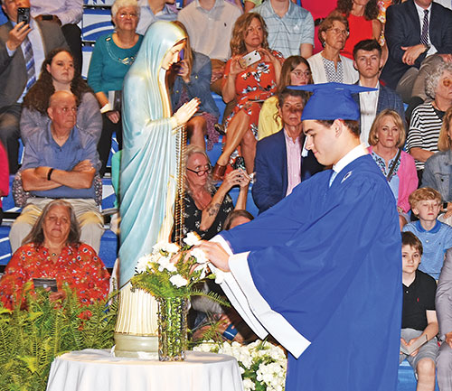 Drew Hasbrook, a member of the Class of 2023 of Bishop Chatard High School in Indianapolis, places a flower in a vase before a statue of the Blessed Mother during the archdiocesan North Deanery high school&rsquo;s graduation last May. It&rsquo;s one of the ways the school honors Mary, its patroness, during the month dedicated to her. (Submitted photo)