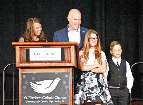 Clarissa and Wade Thaxton smile at their daughter Elanore, whom they adopted through St. Elizabeth Catholic Charities&rsquo; Adoption Bridges of Kentuckiana in New Albany, during their talk at St. Elizabeth&rsquo;s Giving Hope-Changing Lives gala on April 18 in Louisville, Ky.  The Thaxton&rsquo;s son Wesley stands at right. (Photos by Natalie Hoefer)