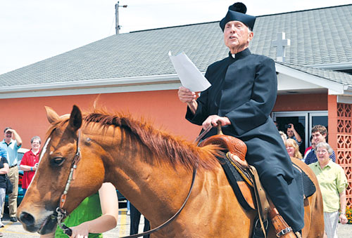 Father Paul Landwerlen, administrator at the time of St. Vincent de Paul Parish in Shelby County, reads a proclamation about the faith community&rsquo;s 175-year history after riding a horse onto its grounds on June 24, 2012. St. Vincent&rsquo;s founding pastor Father Vincent Bacquelin rode on horseback to minister to Catholics throughout central and eastern Indiana. (Criterion file photo)
