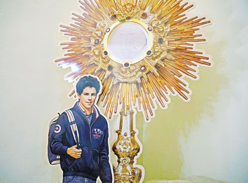 A display showing Blessed&nbsp;Carlo&nbsp;Acutis&nbsp;and a monstrance is seen near his tomb at the Church of Santa Maria Maggiore in Assisi, Italy, in this Oct. 3, 2020, file photo. The U.S. bishops chose Blessed&nbsp;Acutis&nbsp;as the patron of the first year of a three-year National Eucharistic Revival. The Italian teen, who is set to be canonized by Pope Francis, had a great love of the Eucharist and used his technology skills to build an online database of eucharistic miracles around the world. The National Eucharistic Congress will be held on July 17-21 in Indianapolis. (CNS photo/Paul Haring)