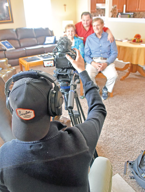 Casey Shaffer of Colorado-based Lux Lab Production House snaps a shot of Mark Hublar, middle, with his parents Linda and Al Hublar in Mark&rsquo;s New Albany apartment on May 29 for a short video featuring Mark to be shown at an evening revival session in Lucas Oil Stadium during the National Eucharistic Revival in Indianapolis on July 17-21. (Photo by Natalie Hoefer)