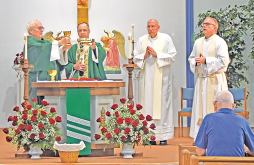 Deacon Steven Gretencord, left, and Archbishop Charles C. Thompson lift the chalice and paten during a Mass in Sacred Heart of Jesus Church in Terre Haute celebrating the faith community&rsquo;s 100th anniversary on June 8. Deacon Gretencord, a son of the parish, was a member of the first class of deacons ordained in the archdiocese in 2008. Father Stephen Giannini, second from right, served as pastor of the parish from 1997-2002 and as its priest moderator from 2010-2013. Father Darvin Winters, right, served as the parish&rsquo;s pastor from 2005-2010 and now serves as its sacramental minister. (Photo by Natalie Hoefer)