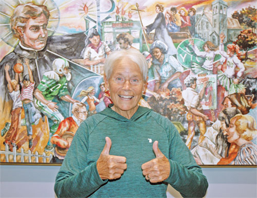 Bernie Price flashes a two thumps-up sign, reflecting how her cancer diagnosis hasn&rsquo;t diminished her joyful approach to life and her dedication to the archdiocese&rsquo;s Catholic Youth Organization, which she has served for 51 years. (Photo by John Shaughnessy)