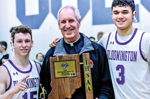 Father Thomas Kovatch poses with Noah Jager, left, and Anthony Leal, both members of St. Charles Borromeo Parish in Bloomington, at Columbus North High School in Columbus in March 2020 after Jager&rsquo;s and Leal&rsquo;s Bloomington South High School boys basketball team won its sectional in the Indiana High School Athletic Association boys basketball tournament. (Submitted photo).