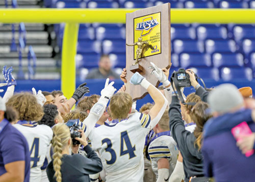 Members of the football team of Our Lady of Providence High School in Clarksville raise Indiana&rsquo;s Class 1A state championship trophy in joy. (Photo courtesy of Jeff McKinley)