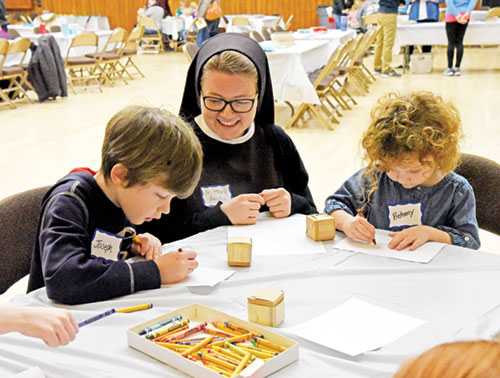 Franciscan Sister Mary Amata Naville smiles while watching Joseph and Bethany Bedwell color at a booth during the Family Day for Vocations on Jan. 18 at the Archbishop Edward T. O&rsquo;Meara Catholic Center in Indianapolis. Joseph and Bethany are members of St. John the Evangelist Parish in Indianapolis. (Photo by Sean Gallagher)