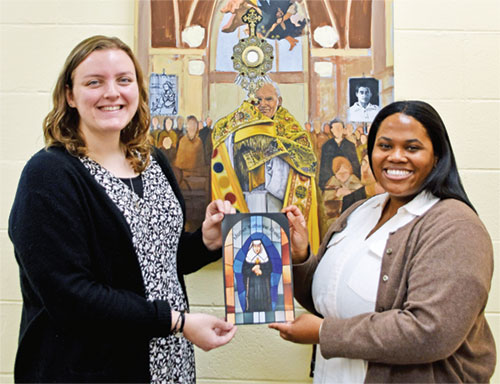 Rachel Levy, left, and Cheyenne Johnson pose in the Archbishop Edward T. O&rsquo;Meara Catholic Center in Indianapolis on March 6 with an image of St. Katharine Drexel, the saint for whom the 2025 National Eucharistic Pilgrimage route is named. Levy, archdiocesan coordinator of young adult ministry, and Johnson, director of Catholic campus ministry at Butler University in Indianapolis, are among the eight young adults selected nationally to be perpetual pilgrims on the 3,300-mile pilgrimage, which departs Indianapolis on May 18 and arrives in Los Angeles on June 22. (Photo by Natalie Hoefer)