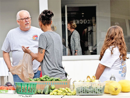 Tony Talbert speaks with a woman at a free vegetable table outside David&rsquo;s House, the ministry building of the Society of St. Vincent de Paul Tri-County Good Samaritan conference, in Richmond on Sept. 10, 2023. (Photo by Natalie Hoefer)