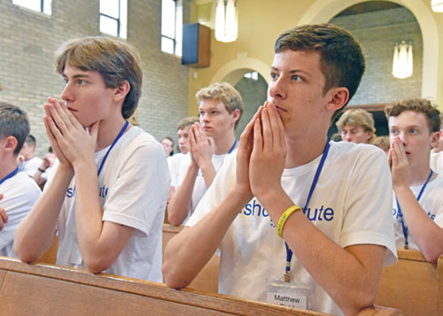 Conrad Otten, a member of St. John Vianney Parish in Fishers, Ind., in the Lafayette Diocese, left, and Matthew Biehl, front row, a member of St. Gabriel Parish in Connersville, kneel in prayer on July 8 during a Mass in the chapel of Bishop Simon Brut&eacute; College Seminary in Indianapolis during the archdiocese&rsquo;s annual Bishop Brut&eacute; Days vocations camp. Also taking part in the camp are Joshua Fuller, second from left, of Our Lady of the Greenwood Parish in Greenwood, and Joshua Skidmore, right, a member of Our Lady of the Most Holy Rosary Parish in Indianapolis. (Photos by Sean Gallagher)