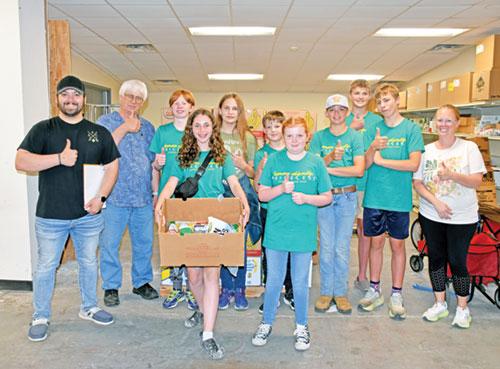 At left, Evan Wise, youth minister for St. Bernard Parish in Frenchtown, St. Joseph Parish in Crawford County and St. Michael Parish in Bradford, poses with youths of the parishes and an adult chaperone at right on June 17 at Harrison County Community Services (HCCS) in Corydon, where the group prepared boxes of food for delivery to the homebound as part of the New Albany Deanery&rsquo;s Summer Daze program. Second from left is Deacon Rick Cooper, executive director of HCCS. (Photo by Natalie Hoefer)