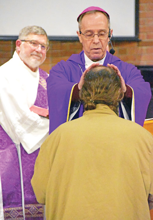 Archbishop Charles C. Thompson, principal celebrant of a Mass at the Plainfield Correctional Facility in Plainfield on March 26, 2023, offers a blessing to a man who was soon to be released from the facility. Deacon Martin &ldquo;Neil&rdquo; May smiles at left. (File photo by Natalie Hoefer)