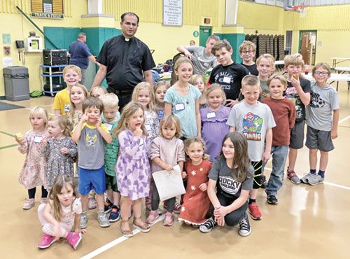 Father Jegan Peter, pastor of St. Vincent de Paul Parish in Bedford and St. Mary Parish in Mitchell, poses in St. Vincent de Paul&rsquo;s school gym with some of the children involved in the two faith communities&rsquo; Family of Faith catechetical program. (Submitted photo)