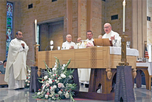 Msgr. William F. Stumpf, archdiocesan vicar general, right, prays the eucharistic prayer during a Sept. 13 Mass at St. Th&eacute;res&egrave; of the Infant Jesus (Little Flower) Church in Indianapolis to celebrate the 100th anniversary of the Indianapolis East Deanery faith community&rsquo;s founding. Concelebrating the Mass are, from left, Father Jude Meril Sahayam, Little Flower&rsquo;s administrator, and retired Father Robert Gilday. Deacon Gary Blackwell, second from right, assists at the Mass. (Submitted photo by Caleb Baue)