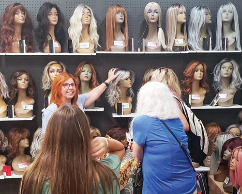 Bonnie Wentworth talks with customers about the upscale wigs she sells in Penelope&rsquo;s Covered Blessings shop in Madison on July 11. A portion of the proceeds from all items sold in the shop, including faith-based merchandise&mdash;both Catholic-specific and general Christian&mdash;go toward helping patients at Norton Cancer Institute in Madison and those suffering hair loss from cancer and other medical conditions. (Photo by Natalie Hoefer)