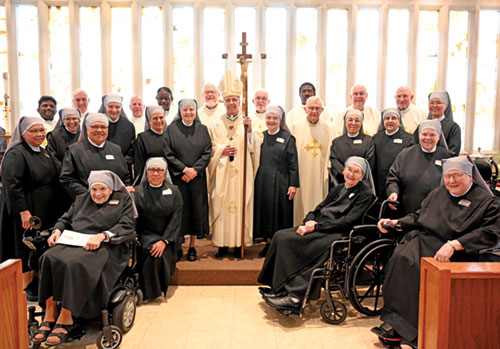 Archbishop Charles C. Thompson and 10 priests pose with professed women of the Little Sisters of the Poor in the chapel of the congregation’s St. Augustine Home for the Aged in Indianapolis on April 30. To the left of the archbishop is Mother General Maria del Monte Auxiliadora, the congregation’s Superior General, who was visiting from France. To his right is Mother Maria Christine, Mother Superior of the St. Augustine Home.