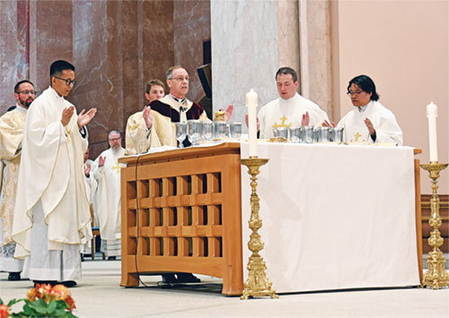 Archbishop Charles C. Thompson prays the eucharistic prayer with newly ordained Father Khaing Thu, left, Father Samuel Hansen and Father Timothy Khuishing during their ordination Mass on June 6 at SS. Peter and Paul Cathedral in Indianapolis. (Photo by Natalie Hoefer)