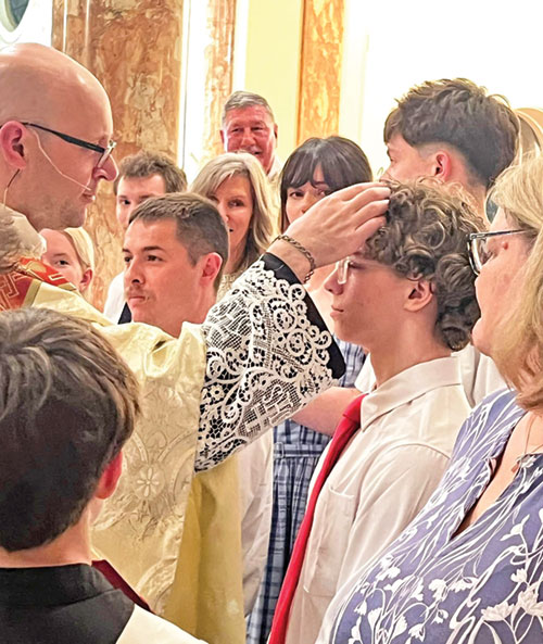 Dylan King receives the sacrament of confirmation as Father Michael Keucher traces the sign of the cross on his forehead during the Easter Vigil Mass at St. Joseph Church in Shelbyville on April 4. (Submitted photo)